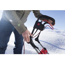 En person använder en snöslunga i snön.