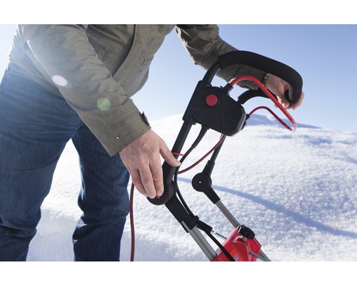 En person använder en snöslunga i snön.