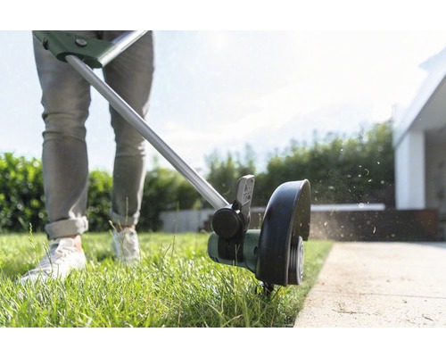 En person klipper gräskanter med en grästrimmer.