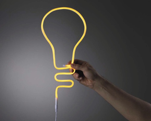 Hand som håller en dekorativ lampa i form av en glödlampa.