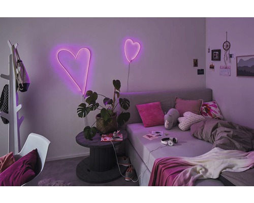 Rum med säng, växt och hjärtformade neonlampor som dekoration