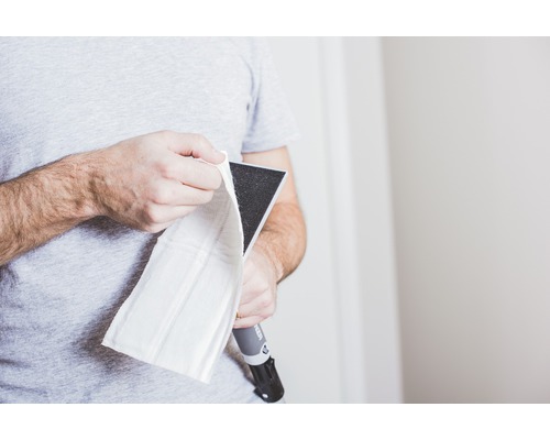 Man fäster ett slipnät på en handslipmaskin