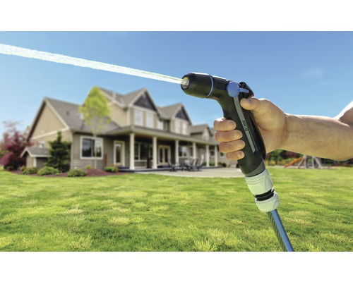 Trädgårdssprutpistol med vattenstråle och hus i bakgrunden