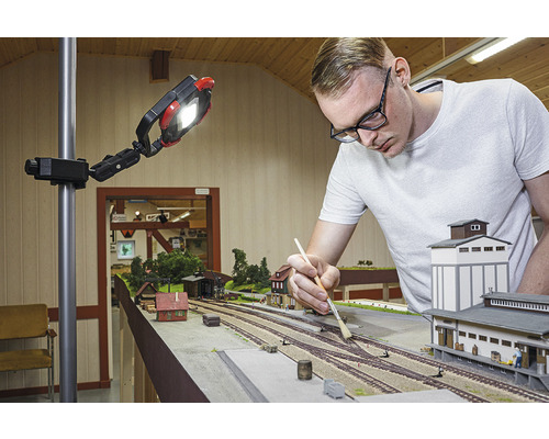 Man arbetar på en modelljärnväg under en arbetslampa.