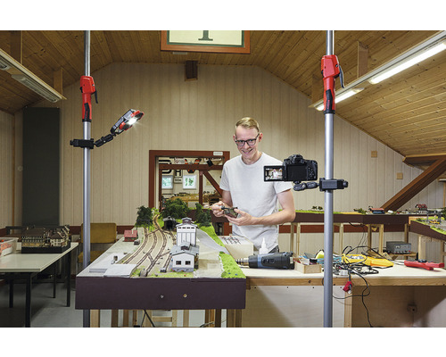 Man filmar en modelljärnväg med en kamera på ett stativ och en arbetslampa.