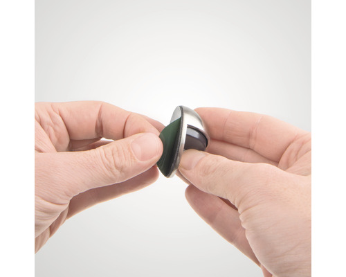 En hand håller en möbelglidare med glidyta i filt.