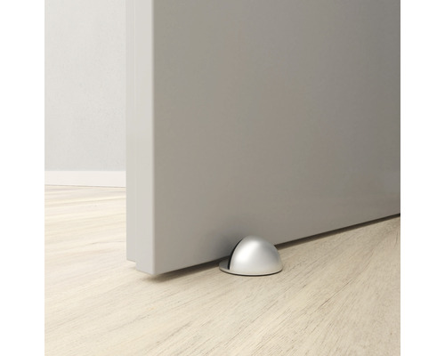 Dörrstopp av metall på golvet framför en dörr