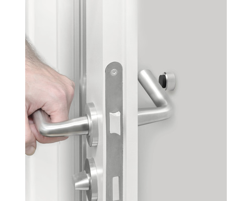 Hand öppnar vit dörr med beslag i rostfritt stål