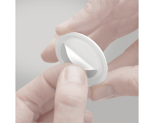 En rund, avtagbar självhäftande dyna hålls i handen.