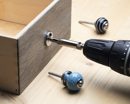 En låda monteras med en sladdlös skruvdragare och en möbelknapp.