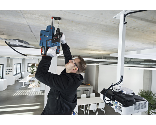 En man borrar ett hål i taket på ett kontor med en borrmaskin