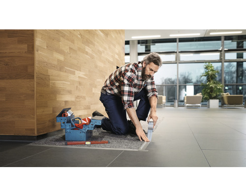 Hantverkare med verktygslåda lägger golvlister i en byggnad