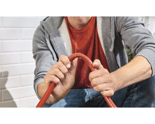 Man håller en läckande trädgårdsslang