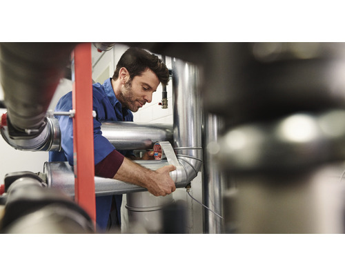 En man lindar ett rör med tätningsband.