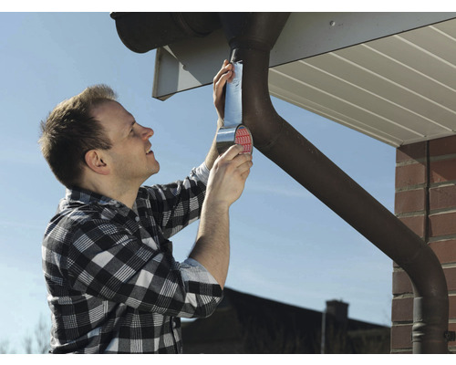 En man reparerar en takränna med tätningsband.