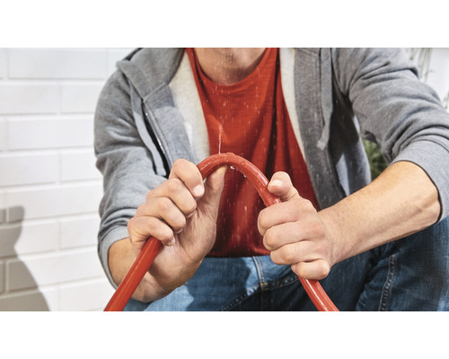 En person håller i en läckande trädgårdsslang.