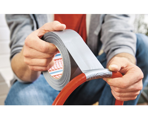 Man reparerar en slang med vävtejp