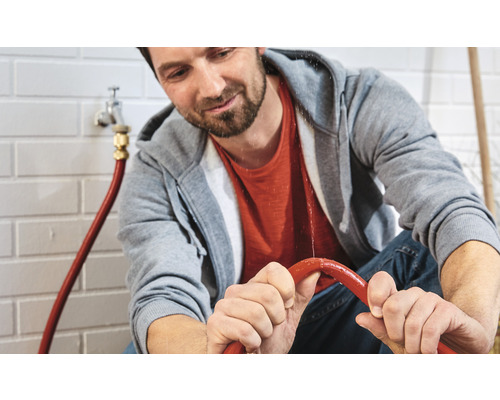 Man inspekterar läckande vattenslangsystem inomhus