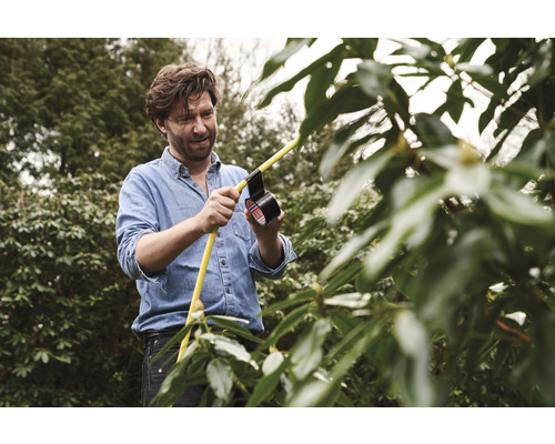 Man reparerar en gul trädgårdsslang med tejp i trädgården.