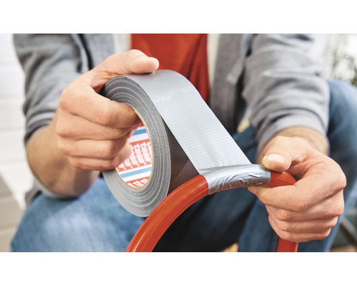 En person använder silvertejp för att reparera ett rör.
