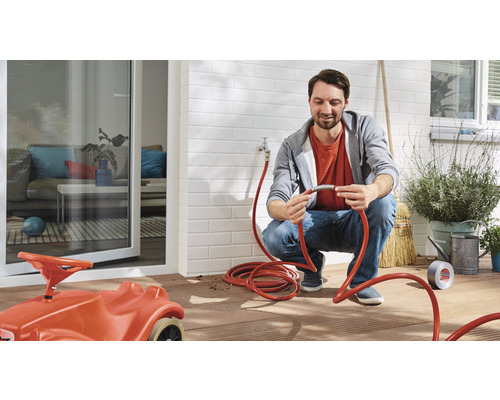 Man som reparerar trädgårdsslang på uteplats med leksaksbil