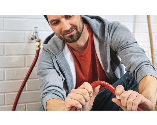 Man reparerar en läckande vattenslang.