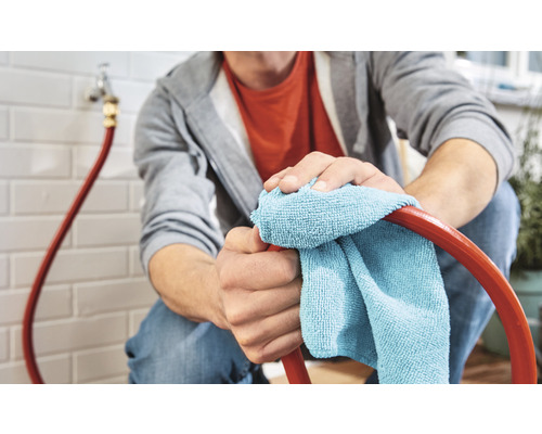 Man rengör en trädgårdsslang med en trasa.