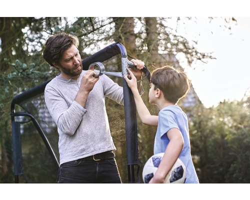 Far och son reparerar ett fotbollsmål med tejp