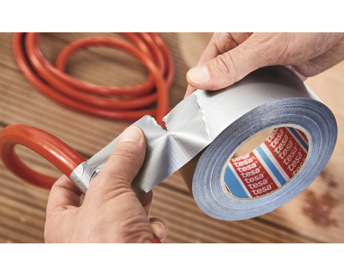 Person som reparerar en slang med silvertejp.