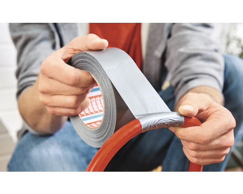 Man reparerar en slang med vävtejp