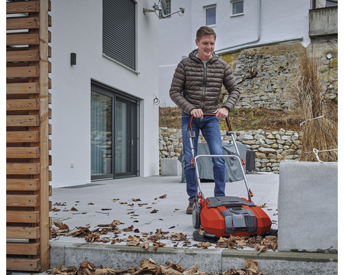 En man använder en utomhus sopmaskin för att ta bort löv.