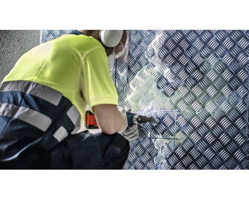 Hantverkare borrar i en räfflad plåtvägg med ett multifunktionsverktyg