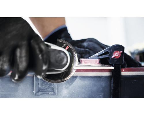 Kakelskärare i bruk med handskar och klämma