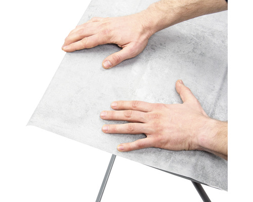 Man fäster möbelfolie på en yta.