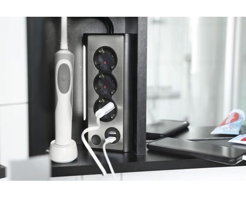 Infälld kontakt med tre uttag och USB-portar i badrummet med ansluten laddare