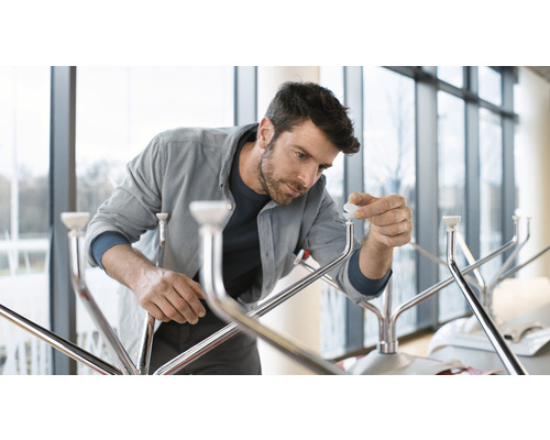 En man monterar en klädhängare med metallfinish och vita ändstycken.