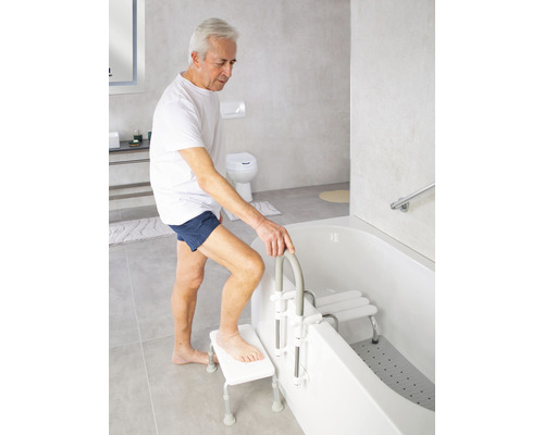 Man använder badlift och badstol i ett ljust badrum.