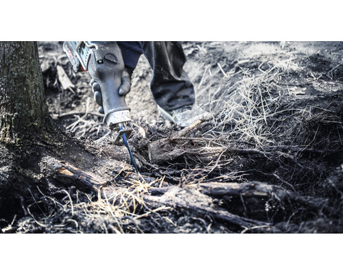 En person använder en tigersåg för att såga av rötter.