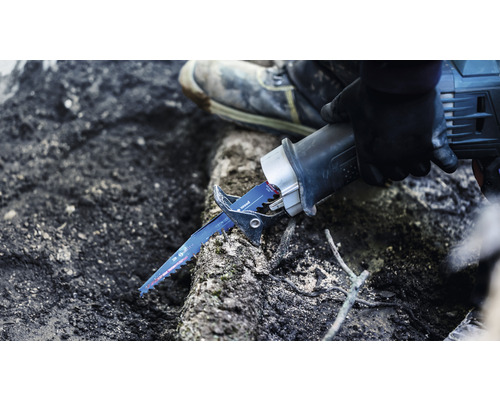 En person använder en tigersåg för att såga trä.