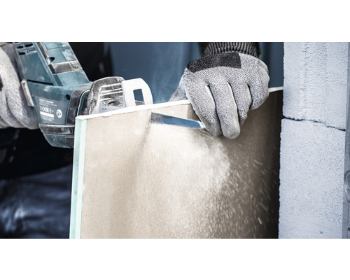 En person sågar en gipsskiva med en såg.