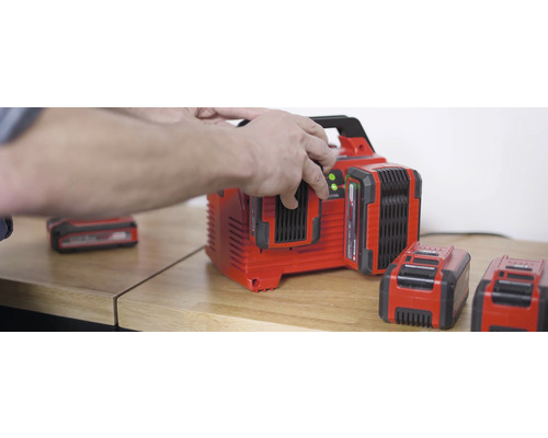 Batteriladdare med flera batterier på ett träbord.