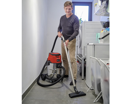 En man använder en våt- och torrdammsugare i en tvättstuga.