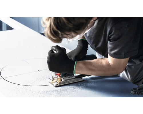 En person sågar en cirkel i en skiva med en sticksåg.