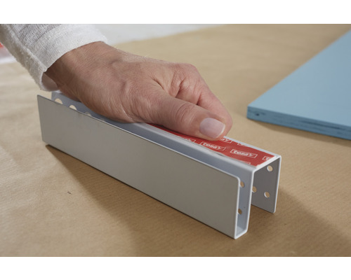 Hand fäster en profil med tejp