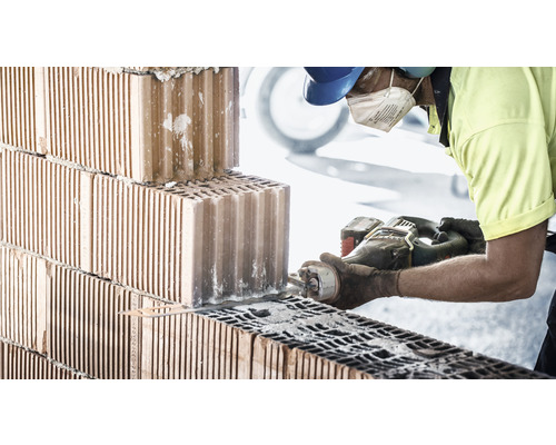 En arbetare sågar en tegelsten med en tigersåg