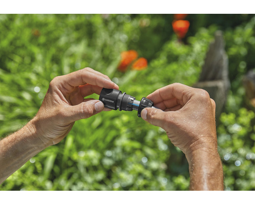 Person kopplar Gardena slangkoppling till trädgårdsslang