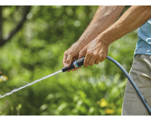 En person använder en trädgårdsslang för att vattna
