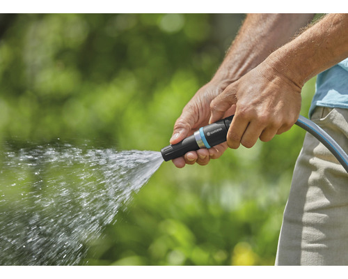 En person håller i en trädgårdsslang med vattenstänk