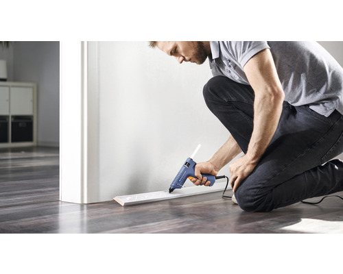 Man fäster golvsockel med limpistol