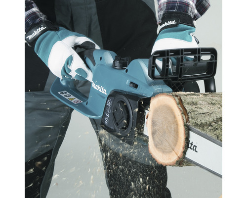 En person sågar en bit trä med en Makita motorsåg.